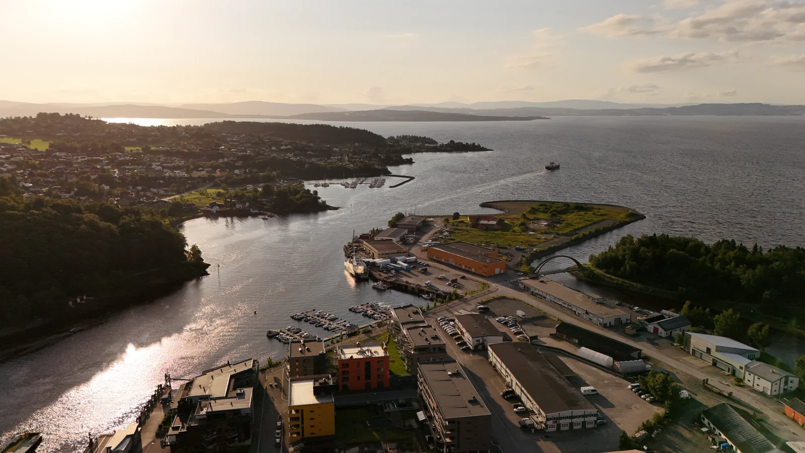 Dronefoto av norsk kystområde med havn og næringsbygg